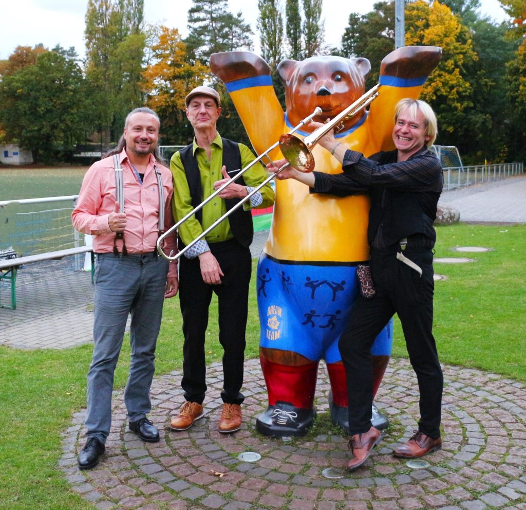 zu sehen sind „The Swingin‘ Steam Engine“ am SF Kladow Buddy-Bären auf dem Vereinsgelände der Sportfreunde Kladow. Es sieht aus als würde der Kladowbär Tuba spielen...